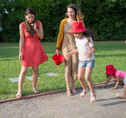 A joyous family experience in a lush Portugal park, featuring playful activities between young girls and adults.